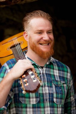 Kızıl saçlı sakallı adam gitar ile