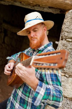 Kızıl saçlı sakallı adam gitar ile
