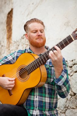 Kızıl saçlı sakallı adam gitar ile