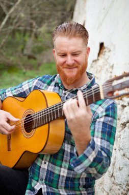 Kızıl saçlı sakallı adam gitar ile