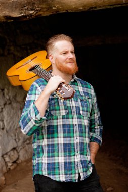 Kızıl saçlı sakallı adam gitar ile