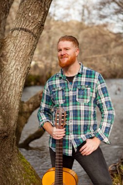 Kızıl saçlı sakallı adam gitar ile