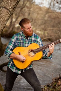 Kızıl saçlı sakallı adam gitar ile