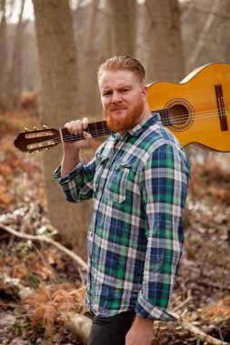 Kızıl saçlı sakallı adam gitar ile