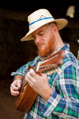 Kızıl saçlı sakallı adam gitar ile