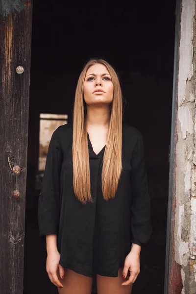 Sensual blonde girl in black shirt waiting near a door — Stock Photo, Image