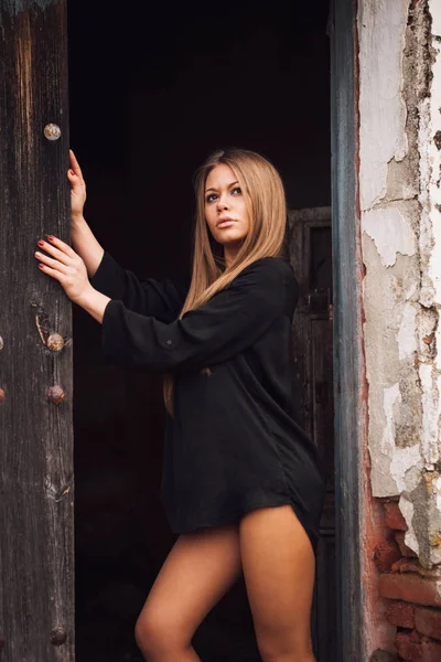 Sensuale ragazza bionda in camicia nera in attesa vicino a una porta — Foto Stock