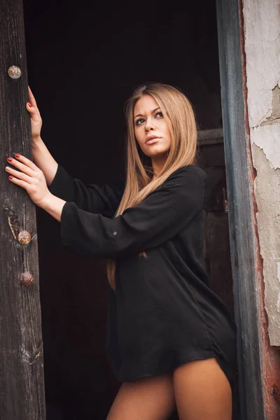Sensuele blond meisje in zwarte shirt te wachten in de buurt van een deur — Stockfoto