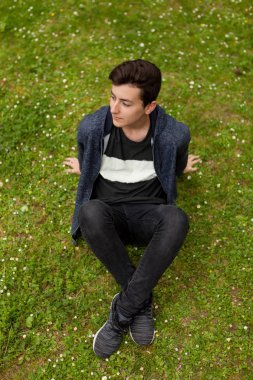 Çocuk parkta çimlere oturup