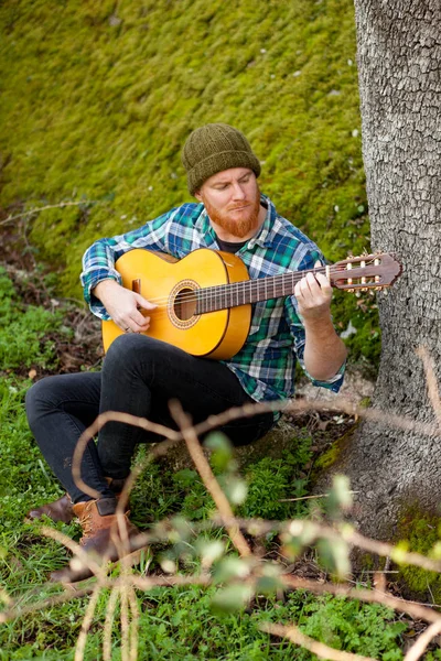 Knappe man met gitaar in de natuur — Stockfoto