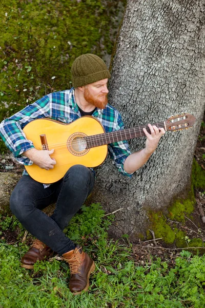 Knappe man met gitaar in de natuur — Stockfoto