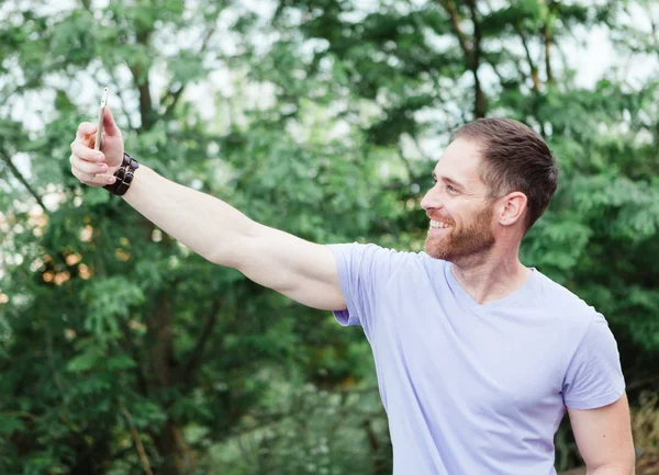 Příležitostné chlap v parku s selfie — Stock fotografie