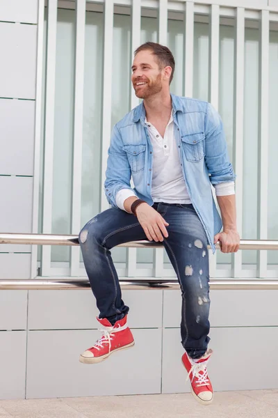 Casual guy sitting on railing in street — Stock Photo, Image