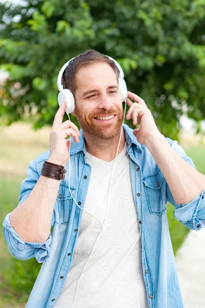 Casual guy in park listening music — Stock Photo, Image