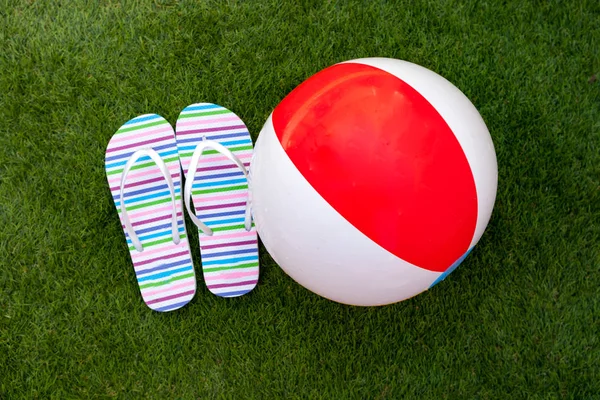 Flip-flops and ball on green grass — Stock Photo, Image