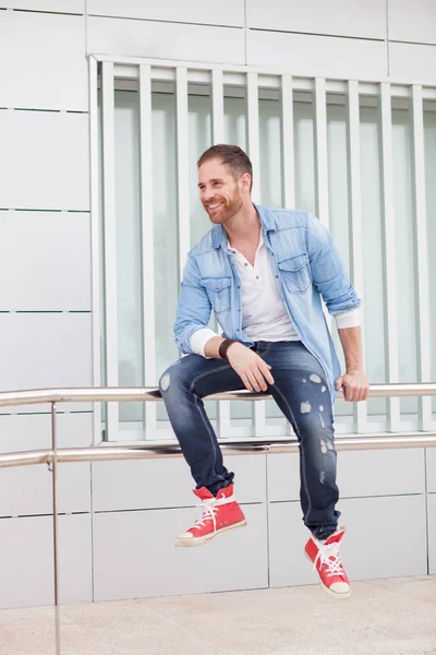 Casual guy sitting on railing in street — Stock Photo, Image