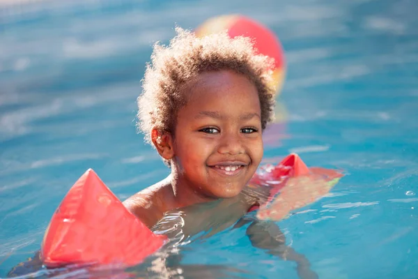 Niño con mangas flotantes nadando en la piscina —  Fotos de Stock