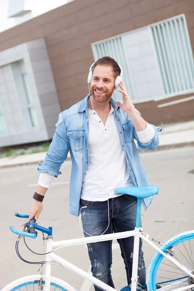 man with bicycle and headphones in city