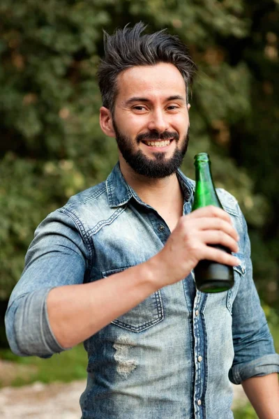 Молодой бородатый мужчина пьет пиво — стоковое фото