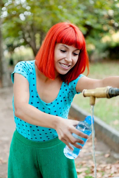 Donna che riempie bottiglia d'acqua in fontana — Foto Stock