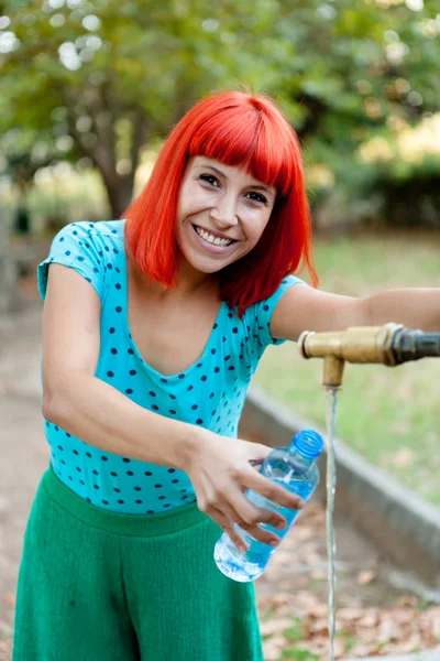 Donna che riempie bottiglia d'acqua in fontana — Foto Stock