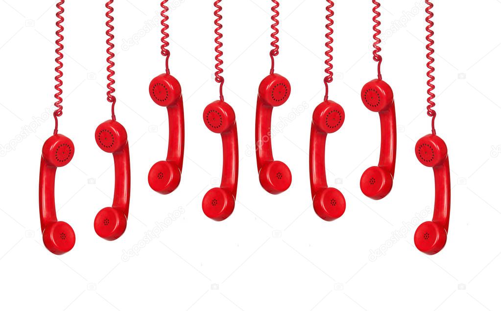 many red vintage telephone handsets hanging isolated on white background