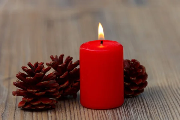 Горящие красные свечи и сосновые шишки — стоковое фото
