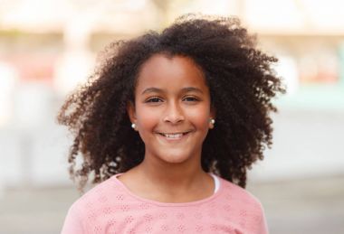 Sokağın ortasında gülümseyen sevimli Afro-Amerikan kız
