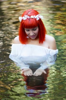 Beyaz elbise ve nehirde Yüzme çelenk giyen güzel genç kadın 