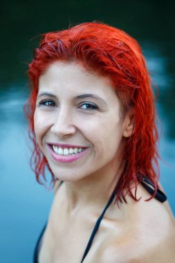 mutlu güzel kırmızı saçlı genç kadın gölde poz mayo 