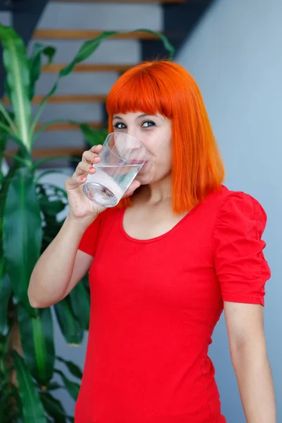 Рыжая Счастливая Женщина Красной Одежде Пьет Воду — стоковое фото