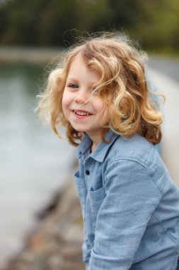 uzun sarı saçlı Nehri yakınında poz mutlu küçük çocuk 
