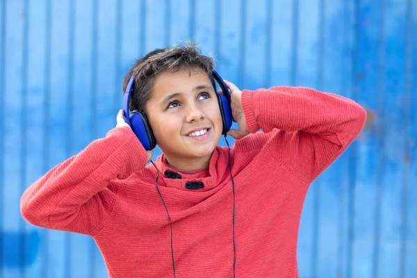 Criança com cabelo escuro ouvindo música com fones de ouvido azuis — Fotografia de Stock