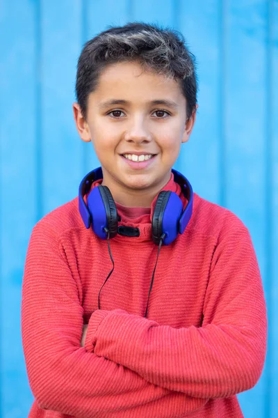 Gyerek sötét hajjal zenét hallgat kék fülhallgatóval — Stock Fotó