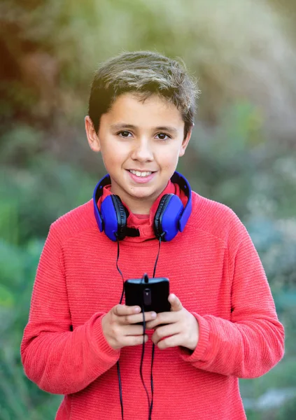 Enfant aux cheveux foncés écoutant de la musique avec des hadphones bleus et un m — Photo