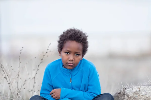 Скучающий ребенок сидит на скале в сельской местности — стоковое фото