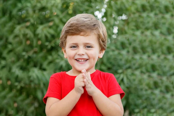 Criança feliz com camiseta vermelha no jardim — Fotografia de Stock