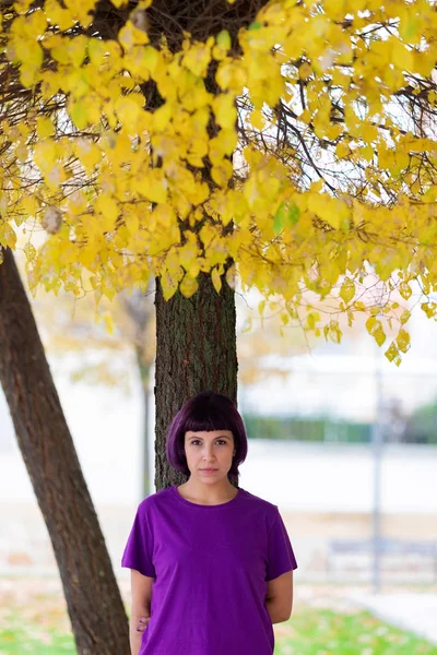 Vrouw in paars met een gele boom van de achtergrond. — Stockfoto