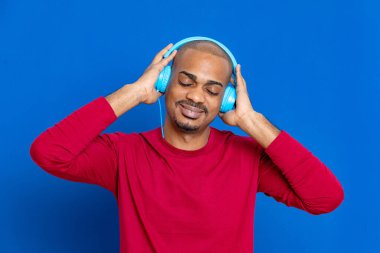 Kırmızı tişörtlü, mavi arka planda Afrikalı bir adam.