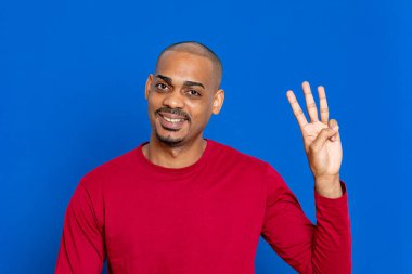 Mavi arka planda kırmızı formalı Afrikalı adam.