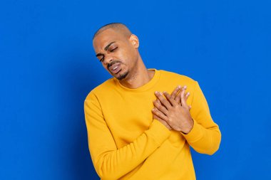 Mavi arka planda sarı formalı Afrikalı adam.