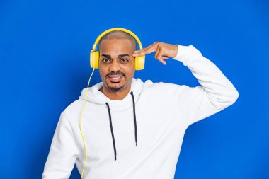 Mavi arka planda beyaz bir kazak giyen Afrikalı adam.