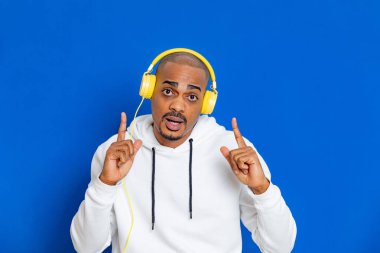 Mavi arka planda beyaz bir kazak giyen Afrikalı adam.