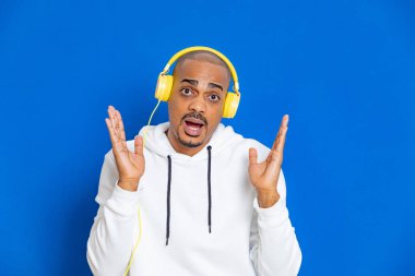 Mavi arka planda beyaz bir kazak giyen Afrikalı adam.