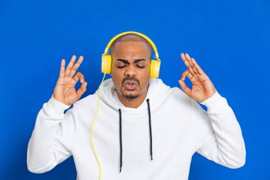 Mavi arka planda beyaz bir kazak giyen Afrikalı adam.