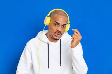 Mavi arka planda beyaz bir kazak giyen Afrikalı adam.