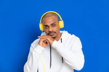 Mavi arka planda beyaz bir kazak giyen Afrikalı adam.