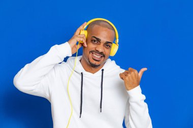 Mavi arka planda beyaz bir kazak giyen Afrikalı adam.