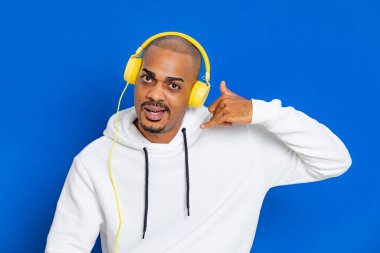 Mavi arka planda beyaz bir kazak giyen Afrikalı adam.