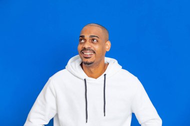 Mavi arka planda beyaz bir kazak giyen Afrikalı adam.